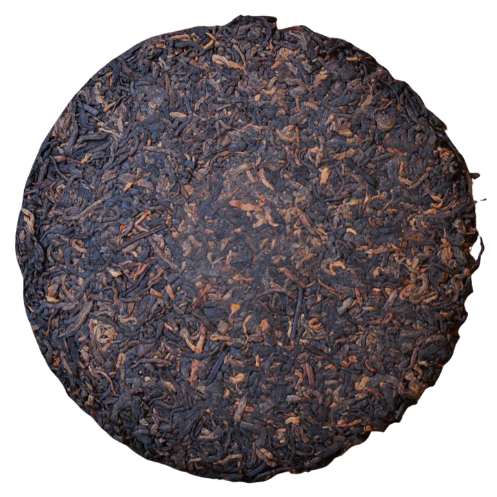 Round compressed Shu Pu'er tea cake with dark brown leaves