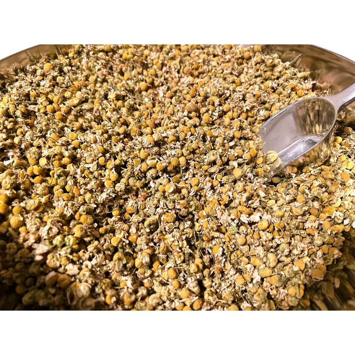 Big bowl of dried chamomile flowers and a metal spoon