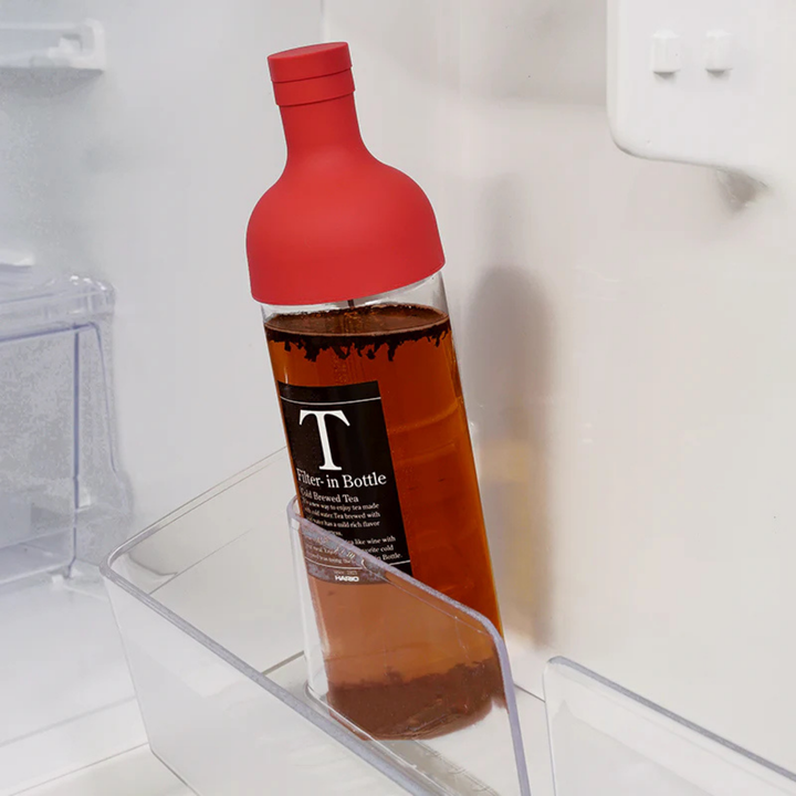 Red cold brew bottle with dark tea in a fridge