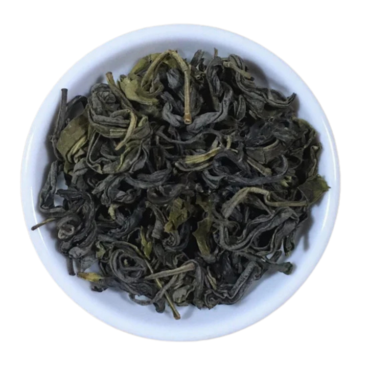Dried curled loose-leaf tea leaves, dark olive green, presented in a small white ceramic plate