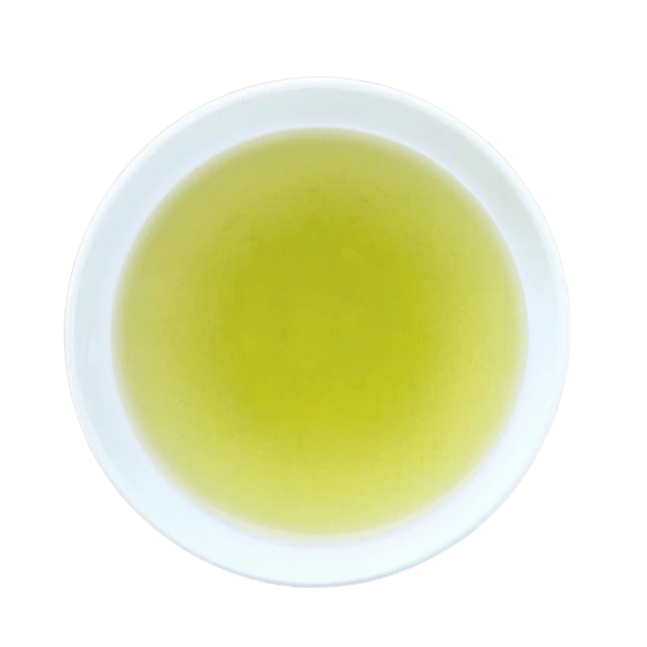 A top-down view of a white ceramic cup filled with yellow-green tea