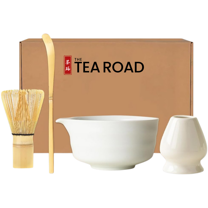 Japanese Matcha set with a white Matcha bowl with a pouring "nose" plus a whisk, a spoon and a whisk holder, all placed in front of 'The Tea Road' branded box.