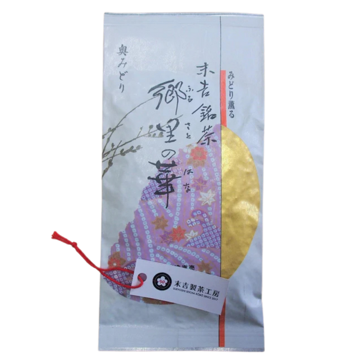 A Japanese tea gift pouch with Japanese text, featuring a pink patterned illustration, a gold circular design, and a red string with a white tag.