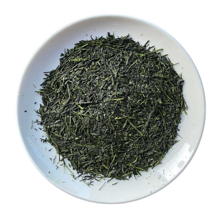 A top-down view of loose-leaf green tea piled in the center of a white ceramic plate