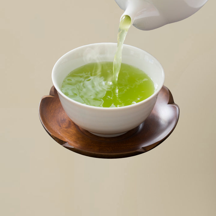 Green tea being poured into a white cup