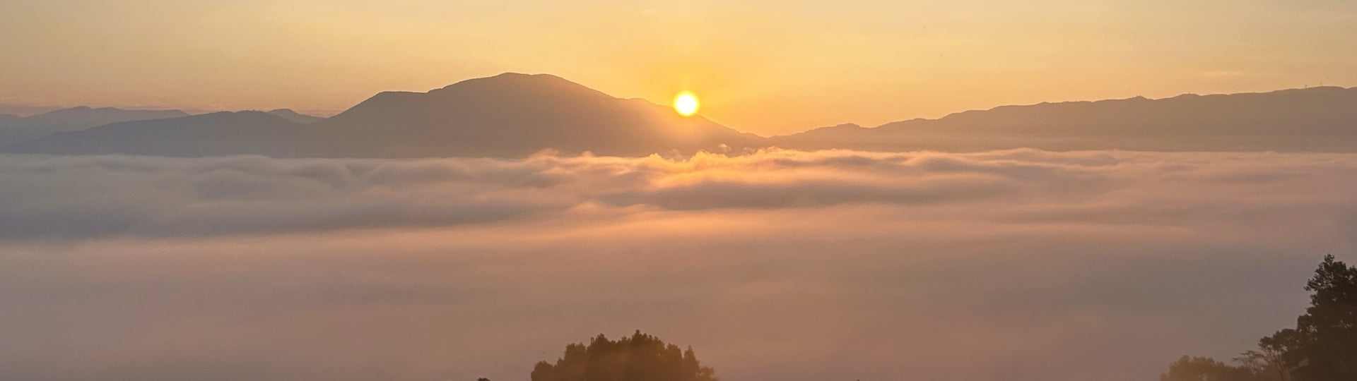 Sunrise over Yiwu mountain in a sea of clouds with mountains in the background