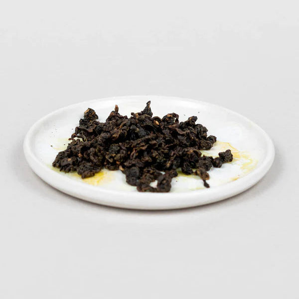 Dry rolled Oolong tea leaves on a white plate