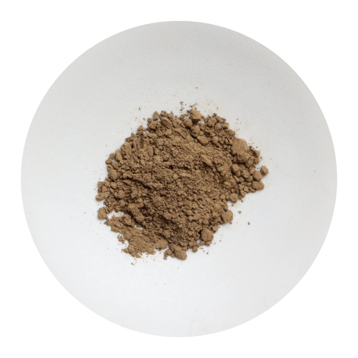A small mound of fine brown hojicha powder centered on a plain white circular plate