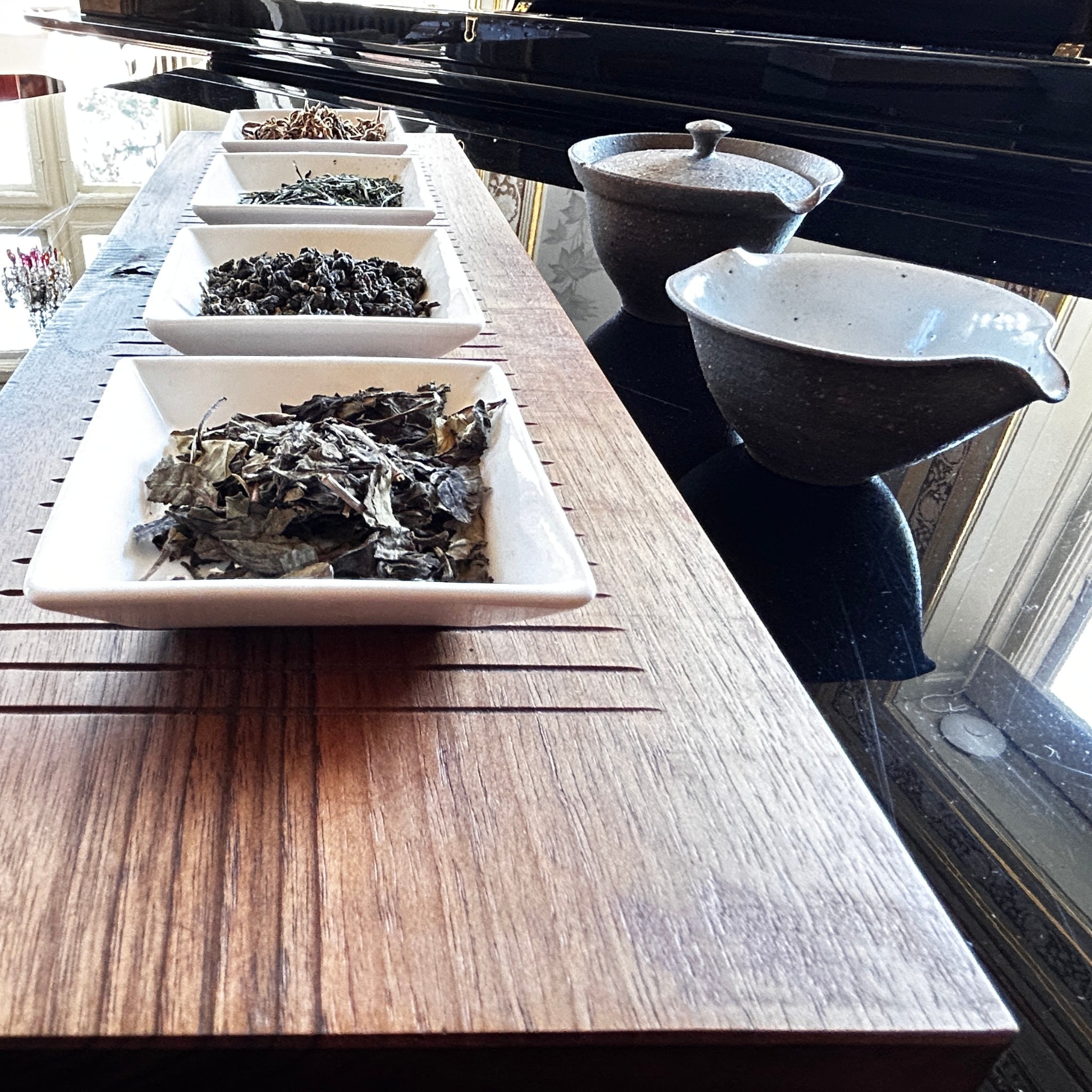 Four white bowls with tealeaves on a grand piano
