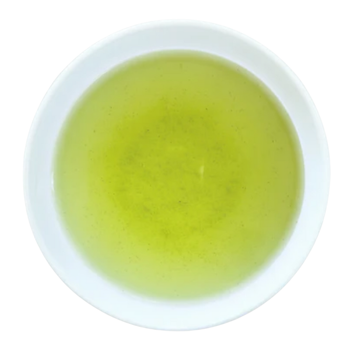A top-down view of a light yellow-green tea served in a white ceramic cup
