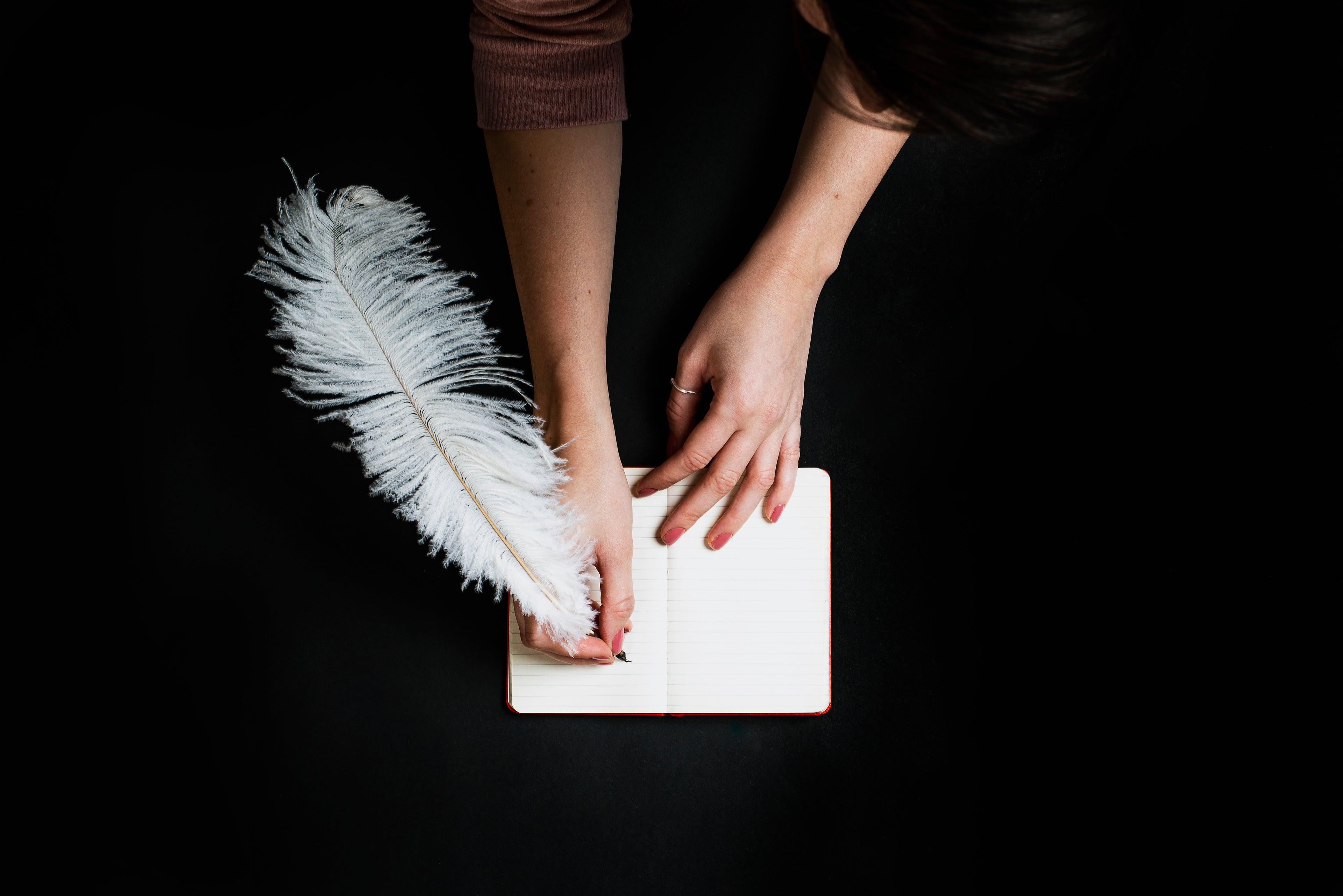 Young woman writing in a notebook on black background