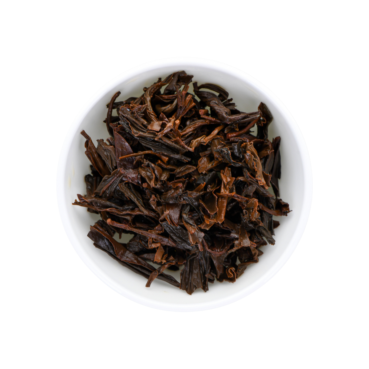 Dark brown wet tea leaves piled in a small white ceramic bowl, photographed from a top-down view