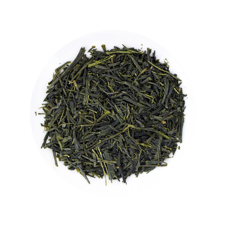 Loose-leaf green tea leaves piled in a circular mound on a white plate