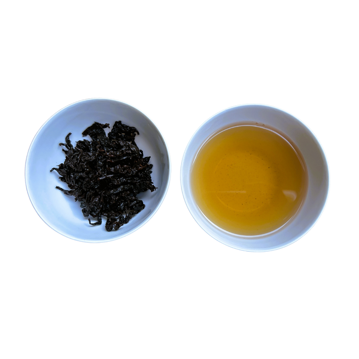 Two white bowls, one with wet tea leaves and the other with brewed tea